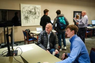 A student shows his project to Rich Teel, Innovations Senior Specialist from the engineering firm, Olsson, during the AI Showcase 